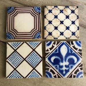 May include: Four square ceramic tiles with blue and white geometric patterns. The tiles have a vintage look and are perfect for adding a touch of traditional style to any space.