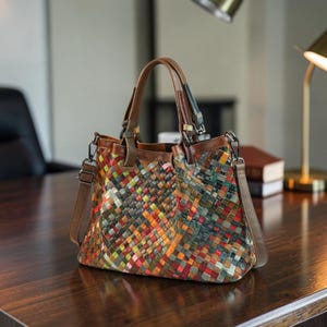 Puede incluir: Un bolso de mano multicolor con un patr&oacute;n trenzado de tiras de cuero en tonos rojo, naranja, verde, azul y amarillo. El bolso incluye dos asas superiores de cuero marr&oacute;n, una correa de hombro desmontable y herrajes met&aacute;licos.