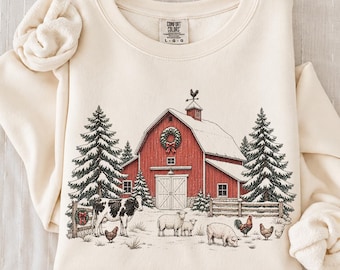 Könnte beinhalten: Ein cremefarbenes Sweatshirt mit Rundhalsausschnitt und einem Grafikdruck einer roten Scheune mit Kranz, schneebedeckten Tannen, einer Kuh, Schafen und Hühnern. Das Innenetikett zeigt den Text Comfort Colors und die Größe L-G.