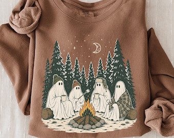 Könnte beinhalten: Ein braunes Langarm-Sweatshirt mit einem Grafikdruck von vier Geistern, die um ein Lagerfeuer in einem Wald sitzen. Die Geister tragen Mützen und halten Tassen, über ihnen sind eine Mondsichel und Sterne sowie Tannenbäume und Baumstämme zu sehen.