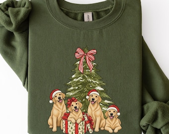 Könnte beinhalten: Ein olivgrünes Sweatshirt mit Rundhalsausschnitt und einer Grafik von vier Golden Retrievern mit roten Weihnachtsmützen vor einem Weihnachtsbaum. Ein Hund sitzt in einem Geschenk mit roter Schleife, und eine rot-weiß gestreifte Schleife ziert die Baumspitze.