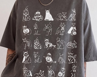 Könnte beinhalten: Ein anthrazitfarbenes Kurzarm-T-Shirt mit einem weißen Grafikdruck von fünfundzwanzig verschiedenen Katzen in diversen Halloween-Kostümen, darunter Geister, Kürbisse, Skelette und Umhänge, die in einem Rastermuster auf der Vorderseite angeordnet sind.
