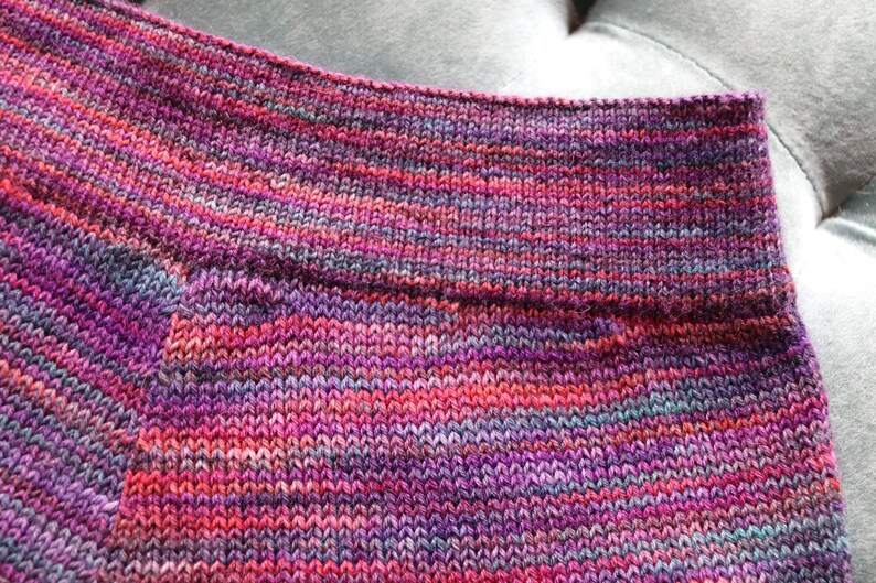 Peut inclure: Gros plan sur un tissu tricot&eacute; avec un motif ray&eacute; multicolore dans des tons de rose, violet et bleu.