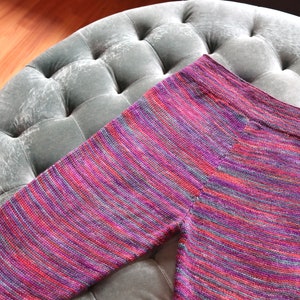 Peut inclure: Un legging ray&eacute; en rose, violet et gris. Le legging est fait d'un tissu doux et tricot&eacute;.