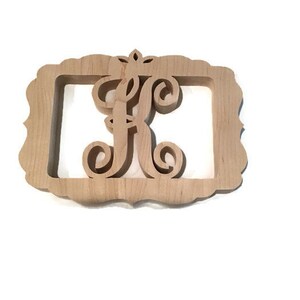May include: A wooden cutout of the letter "F" with a decorative crown above it. The letter is in a simple frame with a scalloped edge.