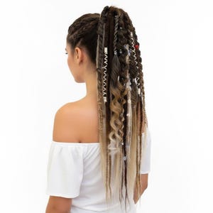 Peut inclure: Une extension de queue de cheval longue composée d'un mélange de dreadlocks synthétiques, de tresses et de boucles lâches dans des tons brun foncé et blond. L'accessoire est orné de perles métalliques argentées et de cordons blancs.