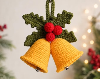 May include: A crochet Christmas ornament featuring two yellow bells suspended from a green holly leaf cluster with three red berries. The ornament hangs from a string and includes small silver-toned metal clappers inside each bell.