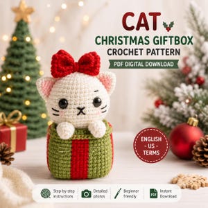 May include: A crochet pattern for a cat in a Christmas giftbox. The cat is white with black eyes, pink inner ears, and a red bow. It sits in a green giftbox with a red ribbon. Text includes CAT CHRISTMAS GIFTBOX CROCHET PATTERN PDF DIGITAL DOWNLOAD.