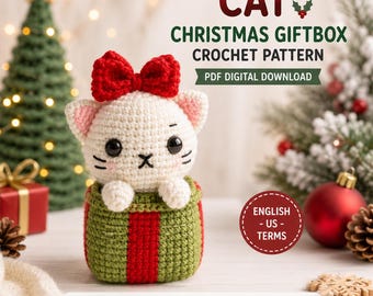 May include: A crochet pattern for a cat in a Christmas giftbox. The cat is white with black eyes, pink inner ears, and a red bow. It sits in a green giftbox with a red ribbon. Text includes CAT CHRISTMAS GIFTBOX CROCHET PATTERN PDF DIGITAL DOWNLOAD.