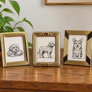May include: Three rectangular picture frames standing upright. The left frame is gold with linear detailing. The center frame is gold with a rounded, stepped edge. The right frame is gold with black corner accents and ribbed sides.