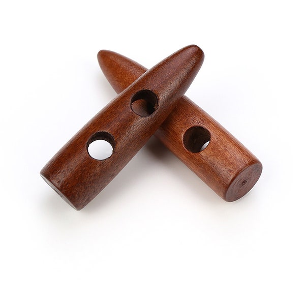 May include: Two brown wooden toggle buttons with two holes each. The buttons are shaped like a bullet and have a smooth, polished finish.