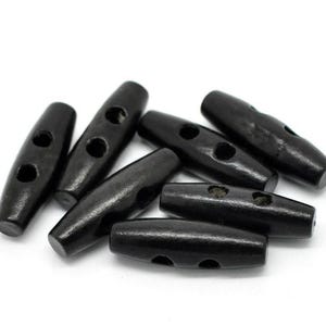 May include: A group of black wooden toggle buttons with two holes each. The buttons are oval shaped and have a smooth, polished finish.