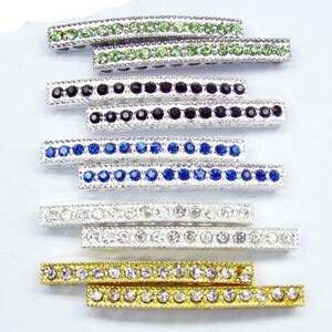 Può includere: Assortimento di barre di metallo argentate con file di strass colorati. Le barre presentano strass verdi, neri, blu, trasparenti e dorati.