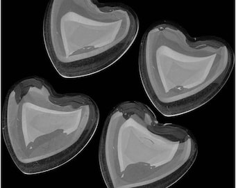 Può includere: Quattro piatti di vetro trasparente a forma di cuore. I piatti sono traslucidi e hanno un leggero bagliore iridescente.