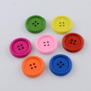 Op de afbeelding: Zes houten knopen in verschillende kleuren: groen, geel, roze, rood, oranje en blauw. Elke knop heeft vier gaten en een verhoogde rand.