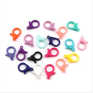 May include: Assortment of colorful plastic lobster claw clasps. The clasps are in various colors, including orange, purple, pink, blue, green, yellow, black, and white.