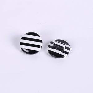 May include: Two black and white striped buttons. The buttons are round and have a glossy finish.