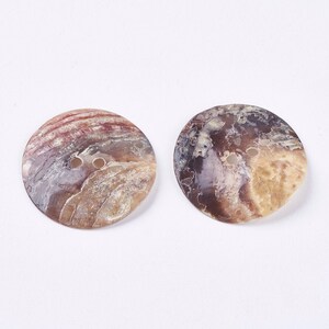 May include: Two round, brown, white, and pink shell buttons with two holes each.
