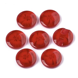 May include: Seven red plastic buttons with a flower design. The buttons are round and have a glossy finish.
