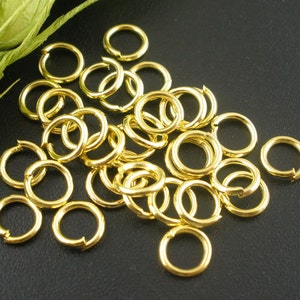 May include: A pile of gold-colored jump rings. The rings are small and round, and they are perfect for jewelry making.