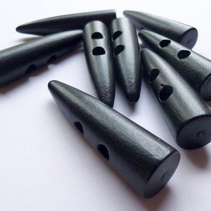 May include: A set of eight black wooden buttons with two holes each. The buttons are shaped like a long, thin, pointed oval.