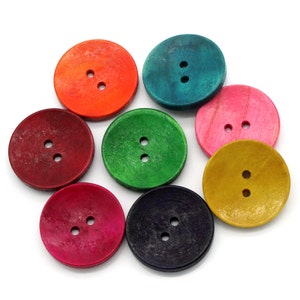 May include: Assortment of eight wooden buttons in various colors, including red, orange, yellow, green, blue, and purple. Each button has two holes and a slightly raised, rounded surface.