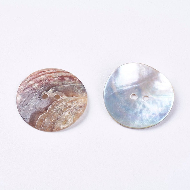 May include: Two round, white, mother-of-pearl buttons with two holes each.