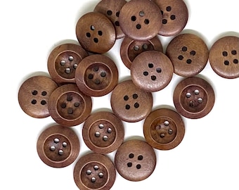 May include: A collection of 15 brown wooden buttons, each with four holes. The buttons are arranged in a random pattern on a white background.