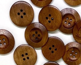 May include: A collection of brown wooden buttons with four holes each. The buttons are arranged in a random pattern on a white background.