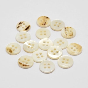 May include: A collection of 15 white and brown shell buttons with four holes each.