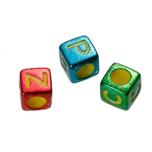 May include: Three colorful letter cubes with yellow letters on a white background. The cubes spell "NO" and "P".