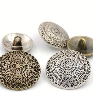 May include: Four decorative metal buttons with a circular, ornate design. The buttons have a silver and bronze finish and feature a raised, intricate pattern.