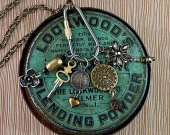 May include: A vintage-style necklace featuring a repurposed teal-colored tin lid with various charms. Charms include a key, a heart, a flower, and a medallion. The lid has text that reads "LOCKWOOD'S BLENDING POWDER". The necklace has a brass chain.