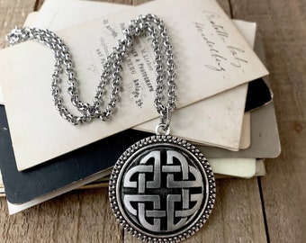 May include: Silver Celtic knot pendant necklace with a chain. The pendant is round and features a detailed knot design.