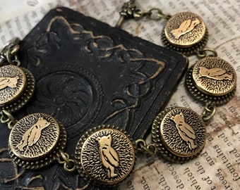 May include: A gold-toned bracelet with a series of round charms featuring a stylized bear silhouette. The bracelet has a toggle clasp.