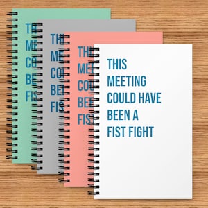 May include: A set of three spiral bound notebooks with the text "This meeting could have been a fist fight" printed on the front of the white notebook. The notebooks are in shades of green, grey, and pink.