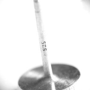 May include: A close-up of a silver metal bottle stopper with the number "575" engraved on the side.