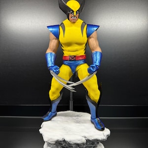 May include: A Wolverine action figure wearing a yellow and blue suit with black shoulder pads, a red belt, and blue gloves and boots. The figure has a black mask with pointed ears, an angry facial expression, and silver claws extending from each hand.