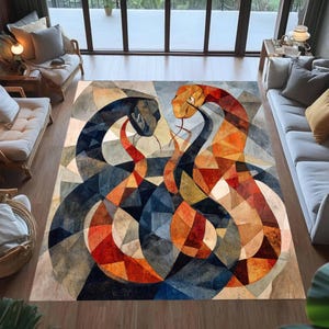 Op de afbeelding: Een rechthoekig vloerkleed met een geometrisch ontwerp in glas-in-loodstijl van twee in elkaar verstrengelde slangen. De slangen zijn uitgevoerd in een palet van diepblauw, zwart, oranje en geel, opgebouwd uit talloze hoekige, veelkleurige driehoeken.