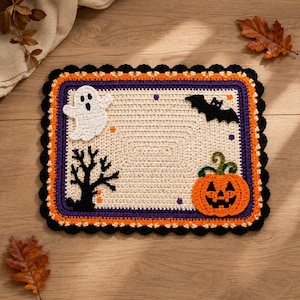 Può includere: Un tappetino rettangolare all'uncinetto con un centro color crema decorato con un fantasma bianco, un pipistrello nero, un albero nero e una zucca arancione. Il bordo è composto da strisce concentriche viola, arancioni e un bordo smerlato nero.