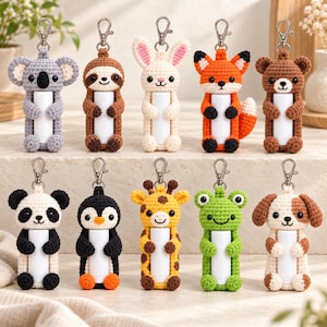 May include: A collection of ten crochet animal lip balm holders, each featuring a silver-toned metal lobster clasp. The characters include a koala, sloth, rabbit, fox, bear, panda, penguin, giraffe, frog, and dog, all holding white tubes.