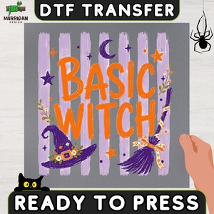May include: A DTF transfer sheet featuring the text BASIC WITCH in orange brush-style lettering over a light purple striped background. The design includes a purple witch hat, a broomstick with a floral ribbon, stars, and a crescent moon.