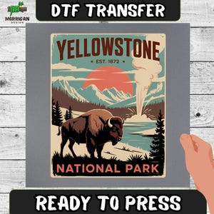 May include: A DTF transfer sheet featuring a graphic of a brown bison standing in front of a geyser, mountains, and a large red sun. The text reads YELLOWSTONE EST. 1872 NATIONAL PARK. The design is printed on a gray background with ready to press text.