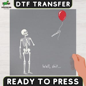 May include: A gray DTF transfer sheet featuring a white skeleton looking up at a detached skeletal hand holding a red balloon. The text "Well, shit..." is printed in white below the skeleton. The design is labeled "DTF TRANSFER" and "READY TO PRESS."