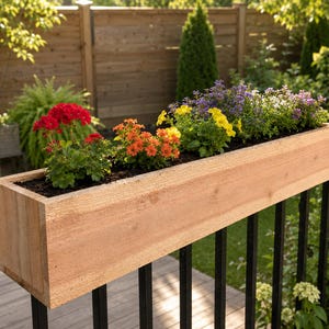 May include: A rectangular light brown wooden planter box mounted on a black metal railing. The planter is filled with dark soil and a variety of vibrant flowers, including red geraniums, orange blossoms, and small yellow and purple blooms.
