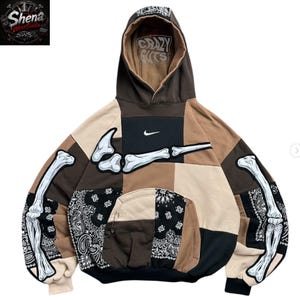 May include: A brown, black, and beige patchwork hoodie featuring a white Nike swoosh logo on the chest, a large white bone graphic across the front and sleeves, and a black and white paisley print. The inner hood displays the text Crazy Guts.