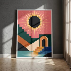 Op de afbeelding: Een rechthoekige wandkunstprint met een donkere cirkelvormige zon met gouden stralen tegen een roze lucht. De compositie bevat geometrische donkergroene trappen, een beige boog en een blauw wateroppervlak met reflecties in een witte lijst.