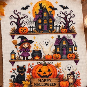 May include: A cross-stitch embroidery on white fabric featuring three horizontal tiers of Halloween imagery including a haunted house, a witch with a broom, a ghost, a black cat, pumpkins, and a sign that reads Happy Halloween in black text.