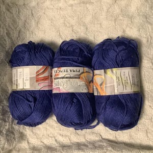 Op de afbeelding: Drie bollen diepblauw Pima Tencel garen van Cascade Yarns. Elke bol heeft een papieren label met de tekst Pima Tencel, Cascade Yarns, 50% Peruaans Pima katoen, 50% Tencel, gewicht 50g, 1,75 oz en 109 yards.