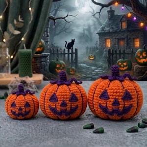 May include: Three crocheted jack-o'-lanterns in varying sizes, each featuring a bright orange body with a dark purple stem and stitched facial features including triangular eyes and a jagged mouth, arranged in a row on a flat surface.